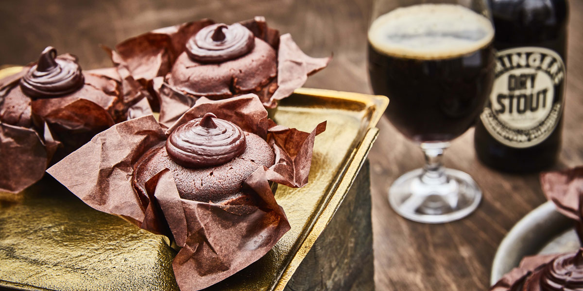 Chocolate and Ale Muffins served on a gold tray, with a bottle and glass of stout in the background