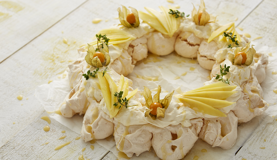 Coconut Meringue Wreath served on baking parchment and drizzled with lemon curd