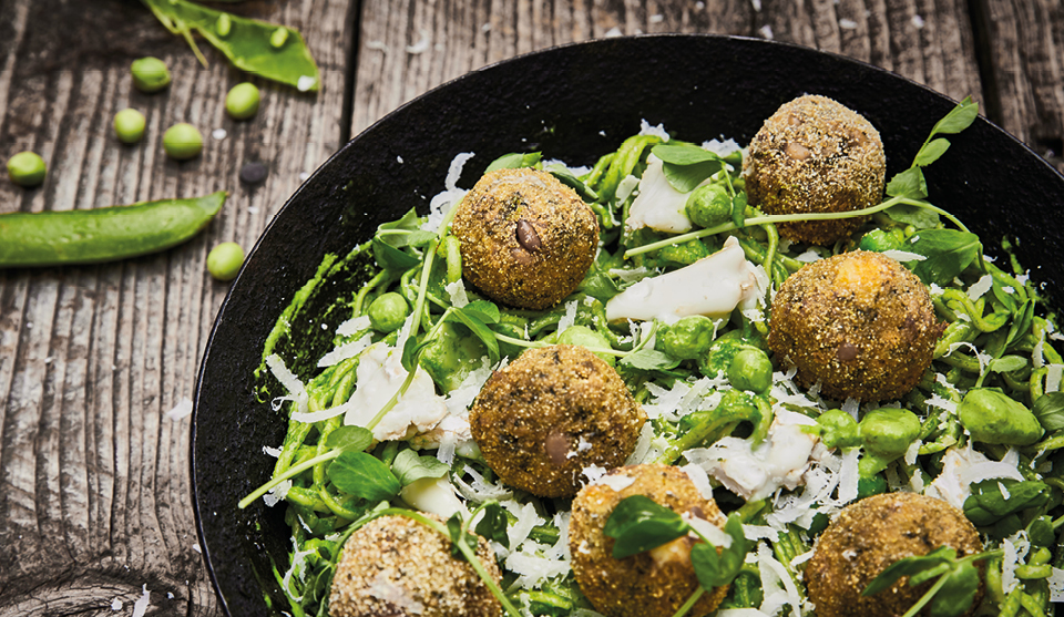 Summer Pea Linguini with Goats Cheese and Polenta Fritters served in a black pan on a wooden table