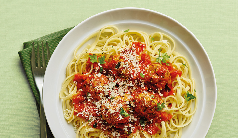 Herby Pork Meatballs with Linguine, served on a white plate, topped with parsley and Parmesan cheese