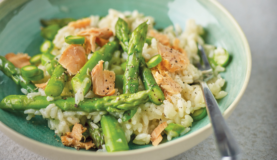 Asparagus and Hot Smoked Salmon Risotto served in a green bowl with a fork placed in the bowl