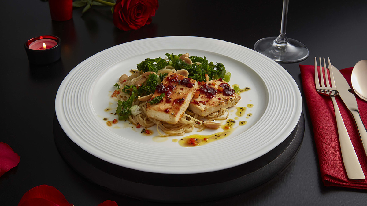 Baked Chilli Tofu, Kale and Sesame Noodles served on a white plate